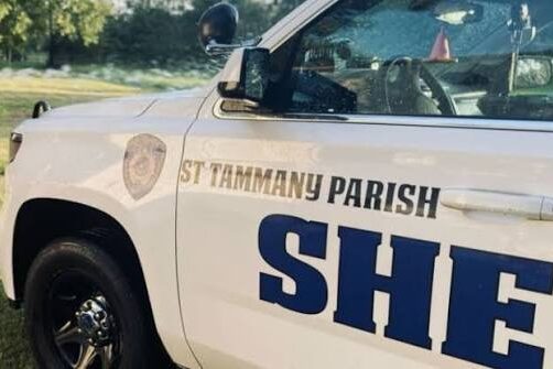 STPSO White sheriff's patrol SUV with 'St. Tammany Parish Sheriff' lettering on the side, parked on grass.