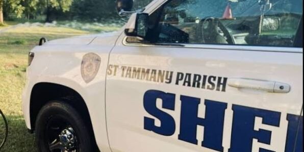 STPSO White sheriff's patrol SUV with 'St. Tammany Parish Sheriff' lettering on the side, parked on grass.