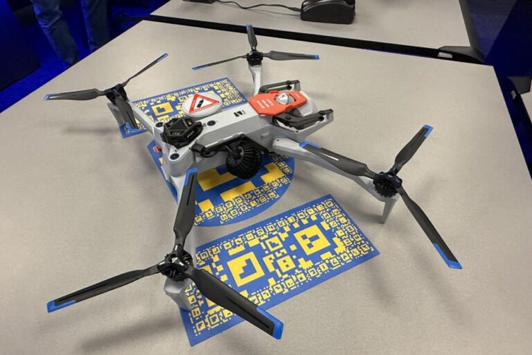 Drone Quadcopter drone with four rotors on a table, with blue-and-yellow QR code cards underneath it.