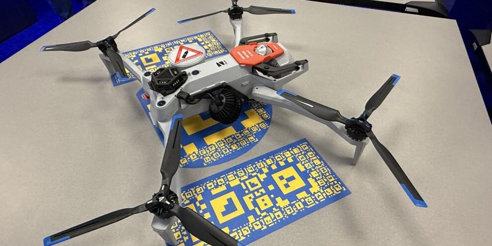 Drone Quadcopter drone with four rotors on a table, with blue-and-yellow QR code cards underneath it.